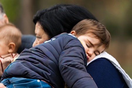 Toddler boy peacefully sleeping on an adult woman's shoulder, finding security and restの写真素材