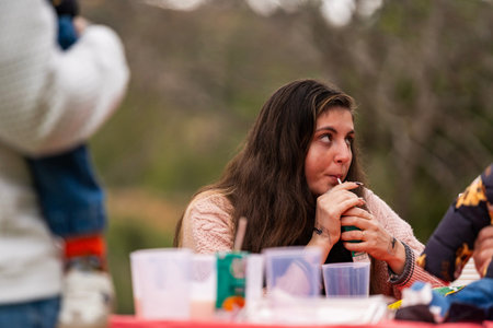 Young woman sipping from a traditional mate gourd with a straw, observing her surroundings