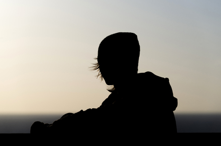 Backlight Young sad teenager looking at the horizon and thinkingの写真素材