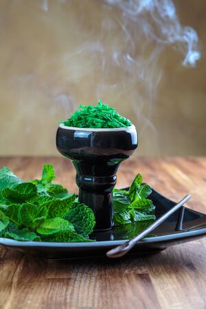 Shisha mint in glossy black cup on a plate with fresh mint leavesの写真素材