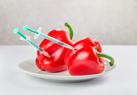 fresh juicy red peppers on a plate, treated with chemicalsの写真素材