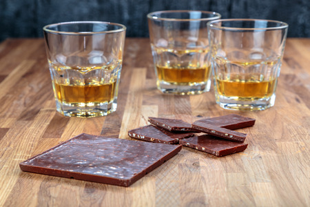chocolate and three glasses of whiskey on the oak surface of the tableの写真素材