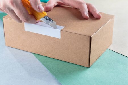 unboxing the parcels Packed in a cardboard box with a utility knife