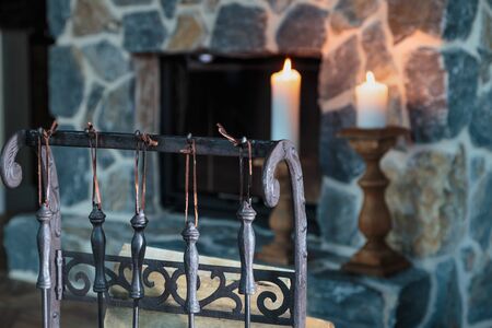 two lighted candles on the massive fireplace of hewn stone on a beautiful wooden floorの写真素材