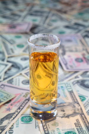 tequila gold on the background of randomly laid out the American dollars of different face value.の写真素材