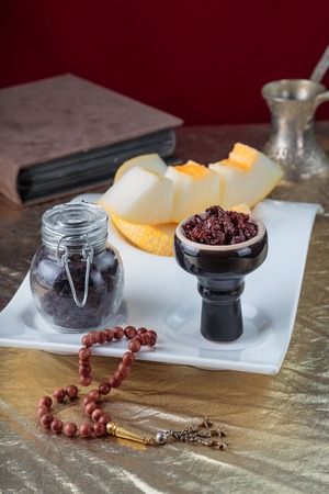 Shisha for hookah Smoking in a black glossy cup stands on a faience tray with melon on a Golden tableclothの写真素材