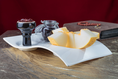 Shisha for hookah Smoking in a black glossy cup stands on a faience tray with melon on a Golden tableclothの写真素材