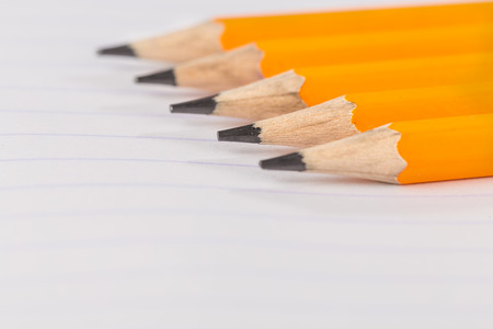 sharpened pencils lying on a notebook sheet in a strip
