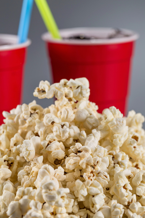 Closeup popcorn on the background of red plastic cups with fizzy drink.の写真素材