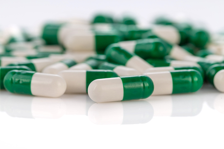 Close-up pile of green-white color medical pills on white backgroundの写真素材