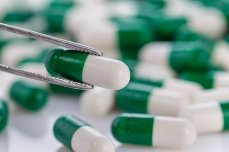pile of green-white color medical pills on white backgroundの写真素材