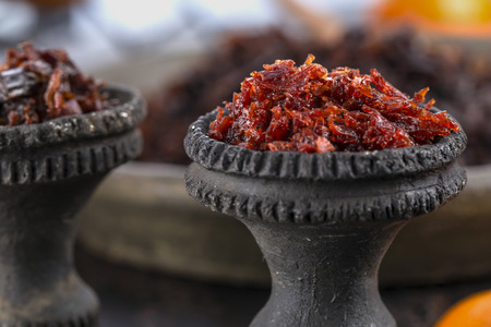 Close-up black burnt ceramic hookah bowl filled with Shisha with Apple flavor. Selective focus.の写真素材