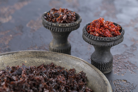 Two black burnt ceramic bowls for hookah Smoking are filled with different types of Shisha. Close up.の写真素材