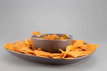 Nachos on a plate with hot sauce. Mexican appetizer.