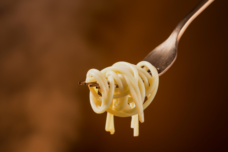 Spaghetti on a fork on a beautiful colored background. Close-up.の写真素材