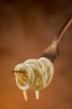 Spaghetti on a fork on a beautiful colored background. Close-up.の写真素材