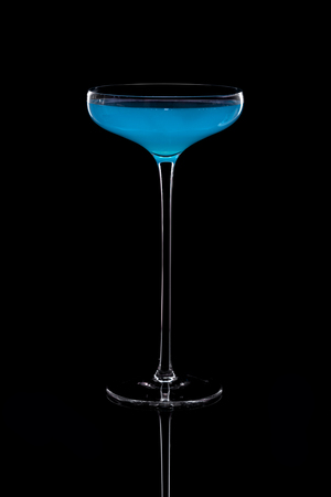 Cocktail based on carbonated drink in a beautiful glass on a thin long leg isolated on black with reflection. Selective focus.の写真素材