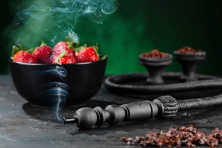 Shisha Smoking hookah in a green bowl on the background of a bowl of strawberries. Selective focus.の写真素材