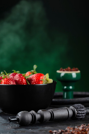 Shisha Smoking hookah in a green bowl on the background of a bowl of strawberries. Selective focus.