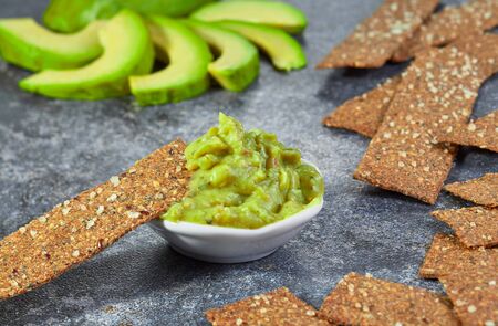 Guacamole in a bowl on a background of sliced avocado. Horizontal.の写真素材