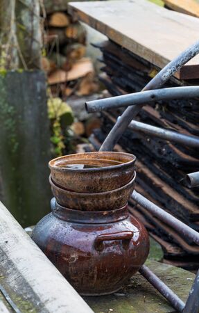 Remains of blackened pottery that survived the fire, against the background of burned boards and metal structures.の写真素材