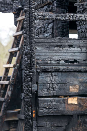 Charred boards of the interior walls of a room that burned in a fire with a staircase in the background.の写真素材