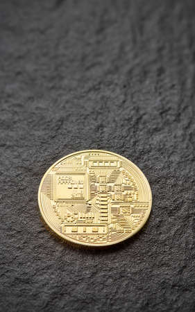 Golden reverse of bitcoin lies on the rough surface of the dark stone. Coin in full sharpness....