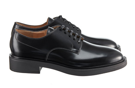 Beautiful pair of classic mens black leather shoes on lace, on the heel, isolated on a white background. Side view.の写真素材