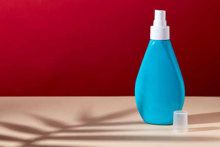 Miniature plastic cosmetic bottle turquoise color, with a spray cap, on the surface of a...