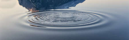 Ripples spreading out in calm water - background imageの写真素材