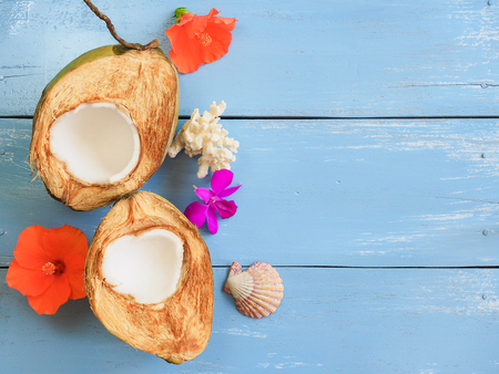 Fresh young coconut with sea shell and flower on blue wooden table for summer fruit concept with copy space.の写真素材