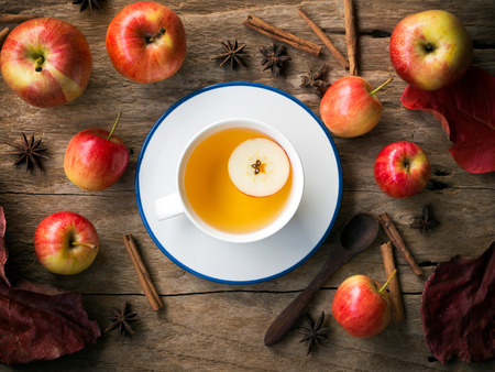 Hot apple tea in white cup on wooden table  for autumn and fall drink concept.の写真素材