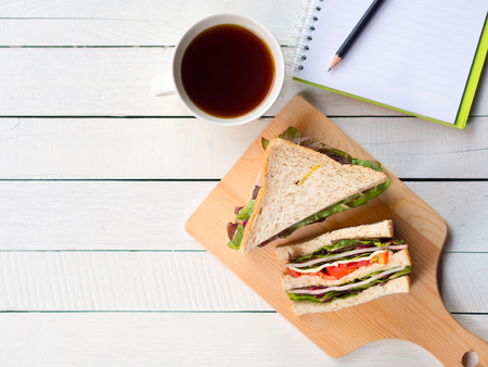 Homemade ham cheese sandwich and coffee cup for breakfast on white working desk in top view with copy space.の写真素材