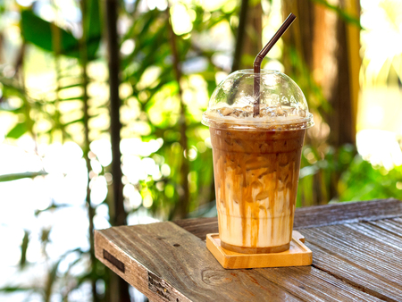 Iced caramel macchiato coffee on wooden table with natural background for summer drink concept.の写真素材