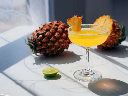 Summer cocktail glass with fresh pineapple and lime, direct sunlight shootingの写真素材
