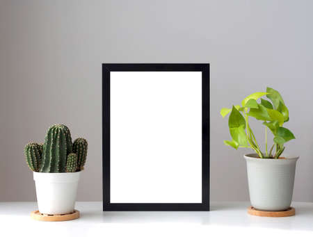 Blank photo frames mockup on the white color desk with pot of plants. Home decoration in minimal styleの写真素材