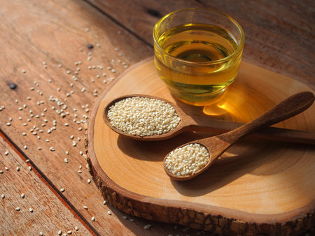 White sesame seeds in wooden spoon and a glass of sesame oil for healthy food concept.の写真素材