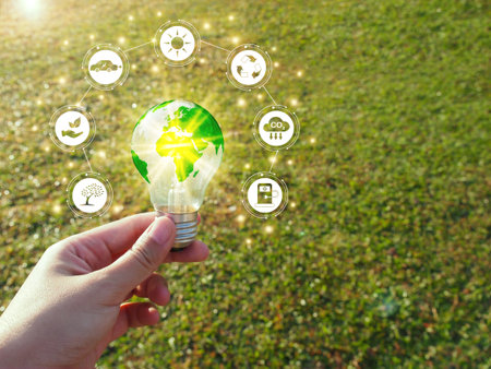 Renewable energy, Electricity, Sustainability concept.
Hand holding lightbulb with green energy icons on nature background.の写真素材