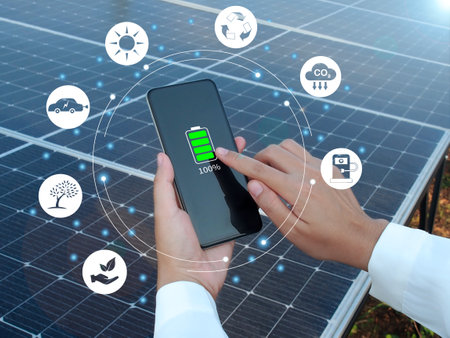Renewable energy, Electricity, Sustainability concept. Woman hold a fully charged phone in hand on a solar panel background.の写真素材