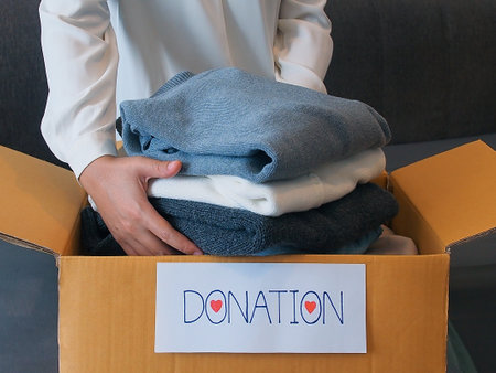 Sustainable lifestyle concept, reusable product. Woman packing clothes into a cardboard box for donation.の写真素材