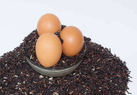 Raw purple Riceberry rice and egg closeup shot in white backgroundの写真素材
