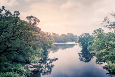 Sunlight colors the river Lune taken from bridge near Kirkby Lonsdaleの写真素材