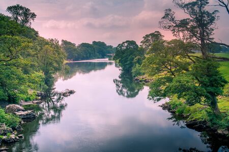 Sunlight colors the river Lune taken from bridge near Kirkby Lonsdaleの写真素材