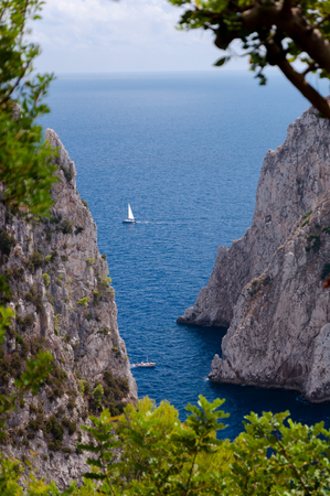 Sea, cliff and Faraglioni view with vegetation frame at Capri - Italyの写真素材