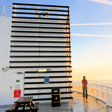 DOVER, UK - AUGUST 24, 2016: The passenger watches the sunrise from the top deck of the ferry.