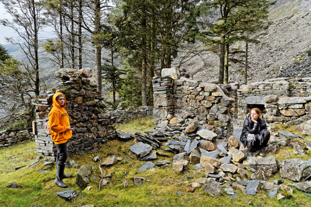 Two girls are exploring the ruins of stone houses in the mountains of Snowdonia National Park, Wales.の写真素材