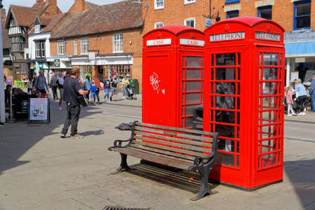 Two red telephone boxes and a street musician playing guitar in Stratford-upon-Avon, April 24, UK...