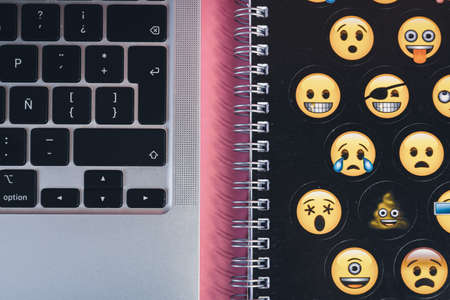 A laptop keyboard and an emoji copybook. Productivity and studying concept. Handwriting.