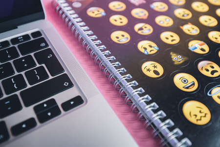 A laptop keyboard and an emoji copybook. Productivity and studying concept. Handwriting.の写真素材