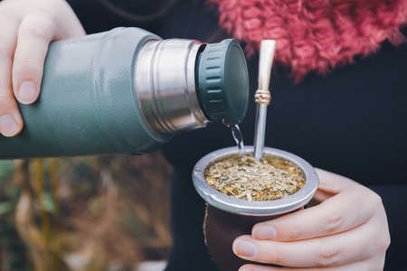 Young woman serving mate. Latin beverage.の写真素材